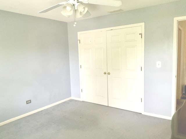 unfurnished bedroom with carpet flooring, a closet, baseboards, and a ceiling fan
