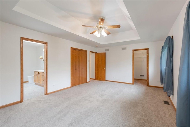 2261 E Gaisor Dr, Crete, IL 60417 - unfurnished bedroom with a raised ceiling, light colored carpet, baseboards, ensuite bathroom, and ceiling fan