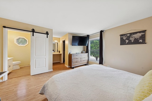 122 E Sherman St, Bartlett, IL 60103 - bedroom with light wood-type flooring, a barn door, ensuite bath, and baseboards