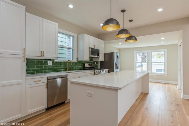 3311 W Belle Plaine Ave, Chicago, IL 60618 - kitchen with appliances with stainless steel finishes, a kitchen island, light wood-type flooring, white cabinetry, and backsplash