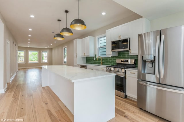 3311 W Belle Plaine Ave, Chicago, IL 60618 - kitchen featuring appliances with stainless steel finishes, a kitchen island, light wood finished floors, white cabinets, and recessed lighting