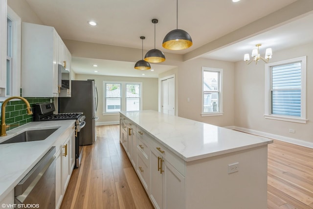 3311 W Belle Plaine Ave, Chicago, IL 60618 - kitchen with appliances with stainless steel finishes, a sink, light wood-type flooring, a kitchen island, and recessed lighting