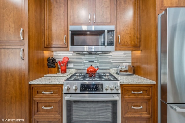 2017 N New England Ave, Chicago, IL 60707 - kitchen featuring stainless steel appliances, brown cabinetry, backsplash, and light stone countertops
