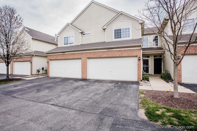 view of front of property with asphalt driveway, a garage, brick siding, and a shingled roof