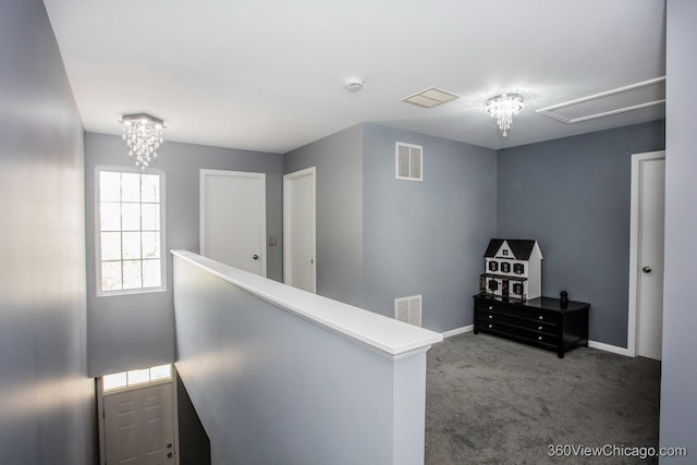 hallway with an upstairs landing, carpet floors, attic access, baseboards, and a chandelier