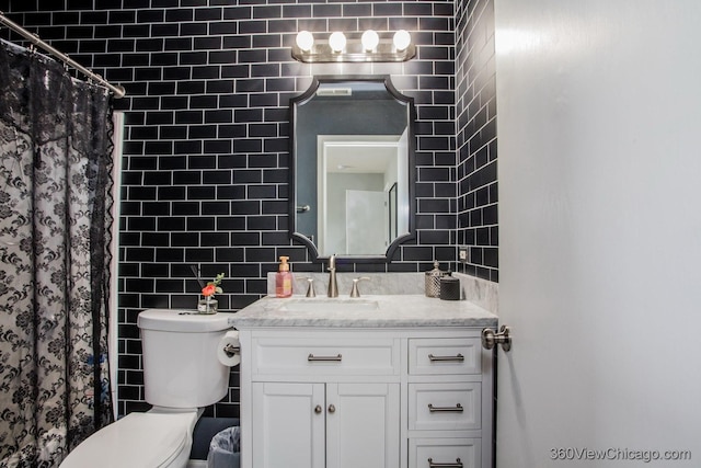 bathroom with tile walls, vanity, toilet, and curtained shower