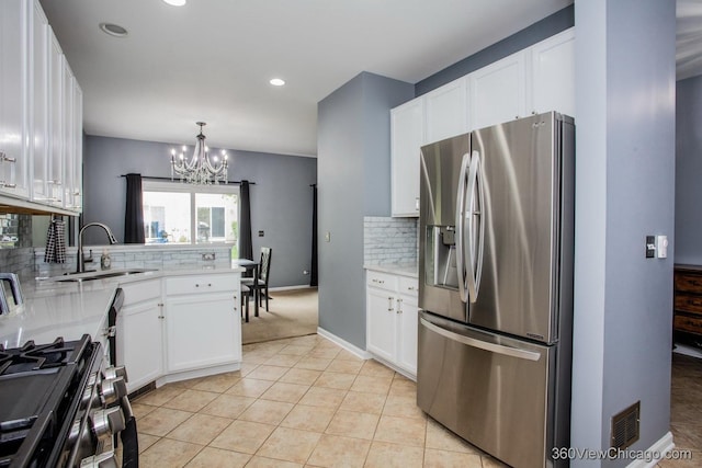 kitchen featuring stainless steel appliances, a sink, a chandelier, light tile patterned floors, and backsplash