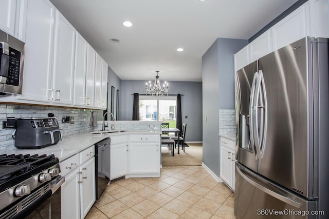 kitchen with stainless steel appliances, a sink, a chandelier, white cabinetry, and decorative backsplash