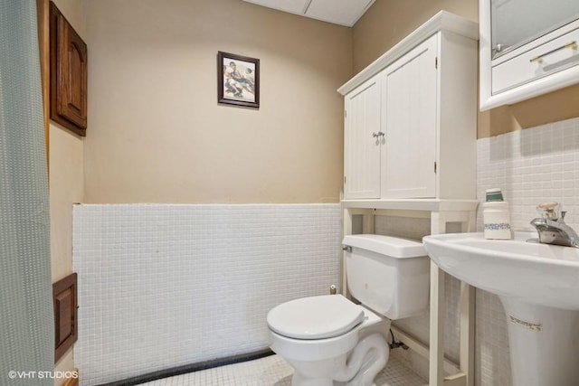 18457 Virginia Ln, Mokena, IL 60448 - bathroom featuring tile walls, toilet, wainscoting, tile patterned floors, and a sink