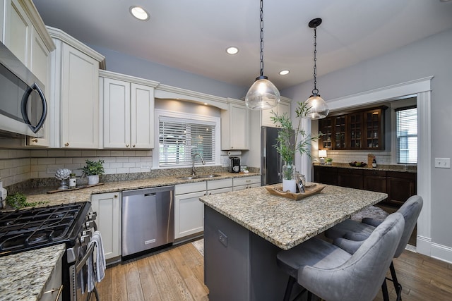 549 S Main St, Naperville, IL 60540 - kitchen with stainless steel appliances, a sink, a center island, light wood-type flooring, and backsplash