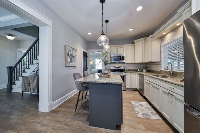549 S Main St, Naperville, IL 60540 - kitchen with appliances with stainless steel finishes, a sink, a kitchen bar, a center island, and light stone counters