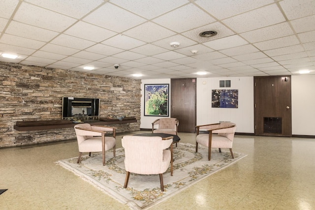 5540 Walnut Ave Unit 23C, Downers Grove, IL 60515 - living room with a stone fireplace, a paneled ceiling, tile patterned floors, and baseboards