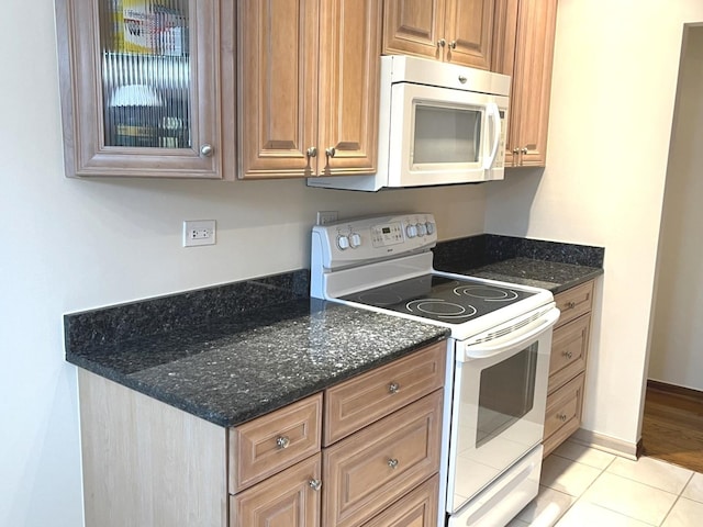 8001 W Courte Dr Unit 307, Niles, IL 60714 - kitchen featuring white appliances, light tile patterned floors, dark stone counters, and brown cabinetry