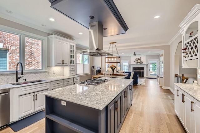 349 Home Ave, Itasca, IL 60143 - kitchen with a sink, island exhaust hood, appliances with stainless steel finishes, a fireplace, and white cabinets