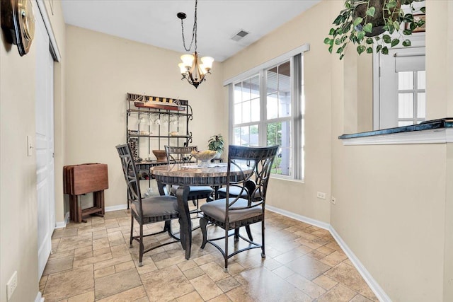 13569 Winterberry Ln, Huntley, IL 60142 - dining space featuring stone tile floors, a chandelier, and baseboards