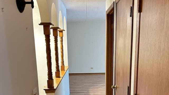 hallway with wood finished floors and a textured ceiling