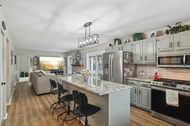 1034 Willoby Ln, Elgin, IL 60120 - kitchen with stainless steel appliances, tasteful backsplash, light stone counters, open floor plan, and light wood-type flooring