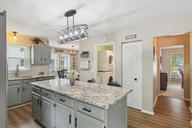 1034 Willoby Ln, Elgin, IL 60120 - kitchen featuring stacked washer and clothes dryer, a sink, gray cabinets, a chandelier, and a center island
