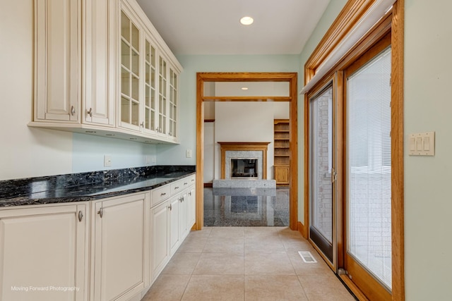 1773 W Whispering Ct, Addison, IL 60101 - kitchen featuring glass insert cabinets, light tile patterned floors, a premium fireplace, recessed lighting, and dark stone counters