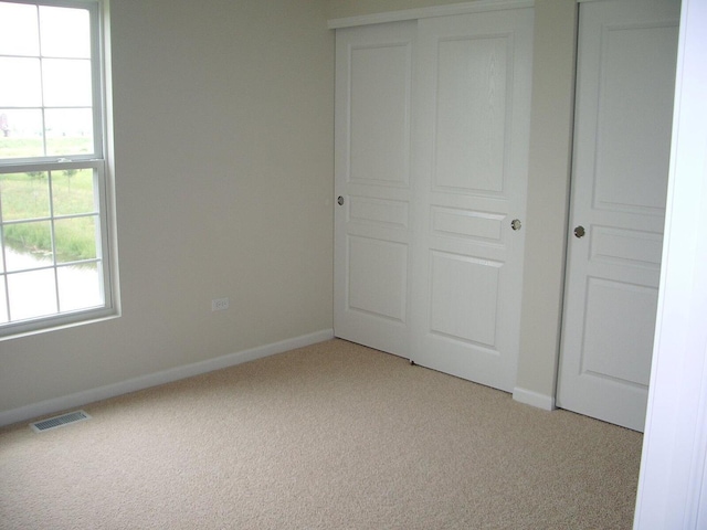 unfurnished bedroom featuring light colored carpet, baseboards, and a closet