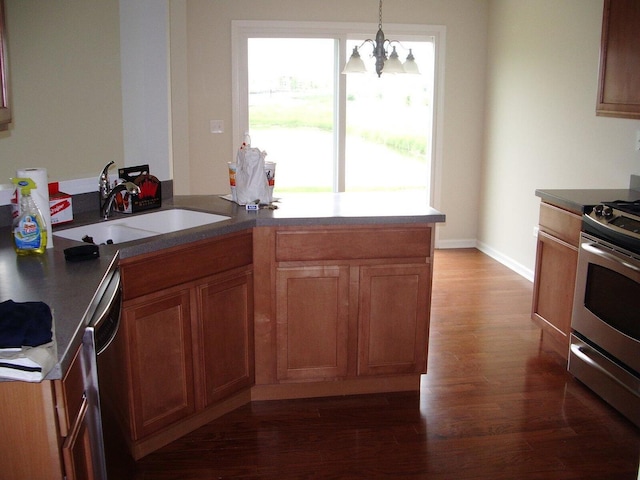 kitchen featuring appliances with stainless steel finishes, a sink, dark wood-type flooring, a chandelier, and brown cabinets