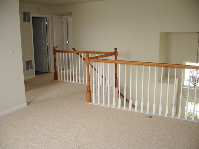 hallway featuring an upstairs landing, carpet flooring, and baseboards
