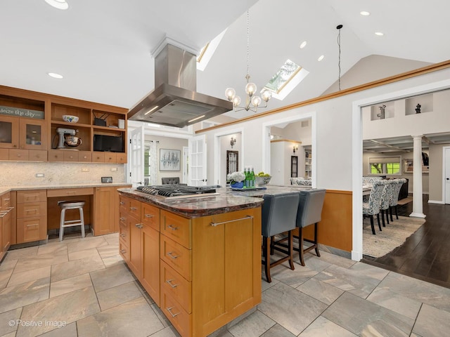 5951 S Grant St, Burr Ridge, IL 60527 - kitchen featuring island exhaust hood, stainless steel gas cooktop, dark stone counters, vaulted ceiling, and a kitchen breakfast bar