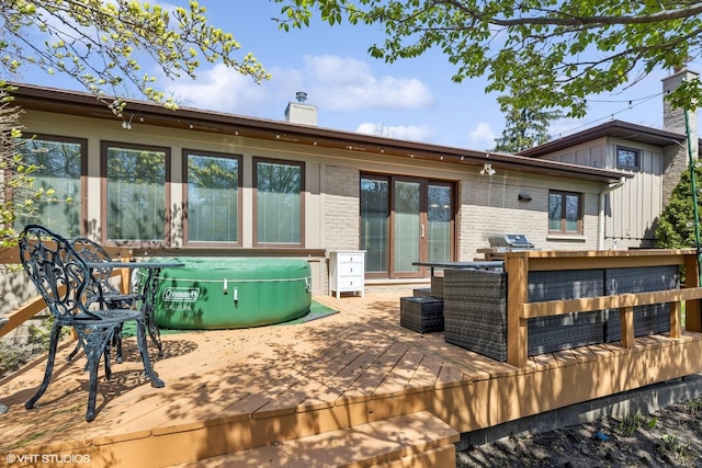 137 Hiawatha Trl, Highland Park, IL 60035 - back of property with a wooden deck, a hot tub, a chimney, board and batten siding, and brick siding