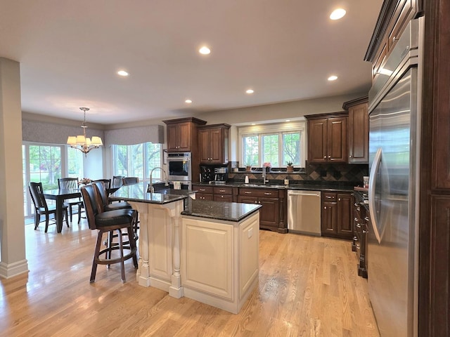 501 Siesta Dr, New Lenox, IL 60451 - kitchen featuring stainless steel appliances, a sink, a chandelier, decorative backsplash, and light wood-type flooring