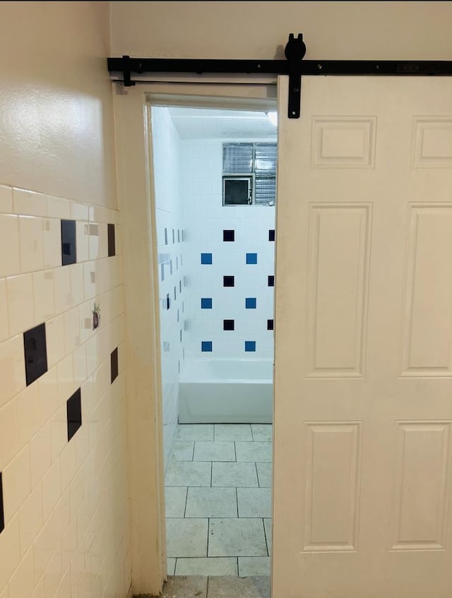 hallway with a barn door and light tile patterned floors