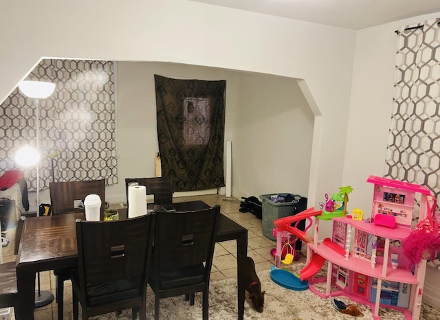 dining space featuring arched walkways and tile patterned flooring