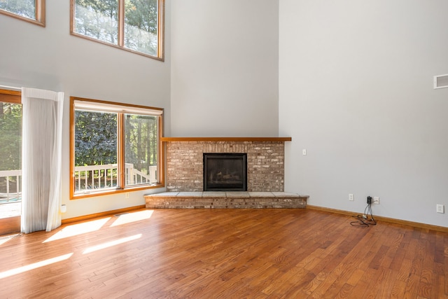 2946 County Road 800 E, Dewey, IL 61840 - unfurnished living room with a towering ceiling, wood finished floors, a fireplace, and baseboards