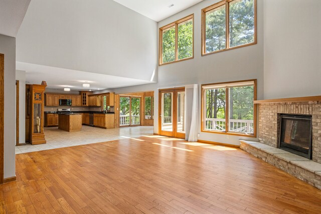 2946 County Road 800 E, Dewey, IL 61840 - unfurnished living room with a high ceiling, light wood-style flooring, plenty of natural light, a brick fireplace, and baseboards