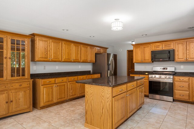2946 County Road 800 E, Dewey, IL 61840 - kitchen with stainless steel appliances, brown cabinets, a center island, dark stone countertops, and light tile patterned floors