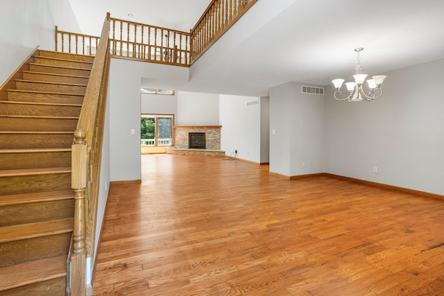 2946 County Road 800 E, Dewey, IL 61840 - unfurnished living room with wood finished floors, a chandelier, stairs, a fireplace with raised hearth, and a towering ceiling