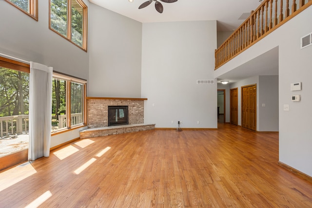 2946 County Road 800 E, Dewey, IL 61840 - unfurnished living room featuring a towering ceiling, wood finished floors, baseboards, ceiling fan, and a fireplace