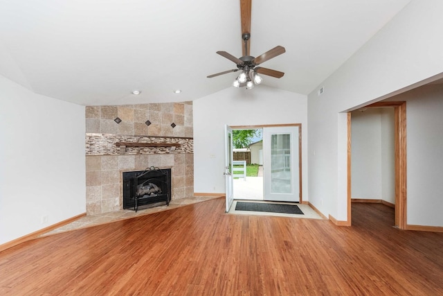 2725 2100n Rd, Minonk, IL 61760 - unfurnished living room featuring wood finished floors, a tiled fireplace, ceiling fan, lofted ceiling, and baseboards
