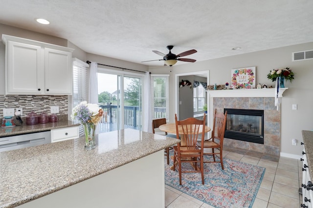 2738 Wharton Way, Normal, IL 61761 - kitchen featuring decorative backsplash, white cabinets, a fireplace, light stone counters, and a ceiling fan