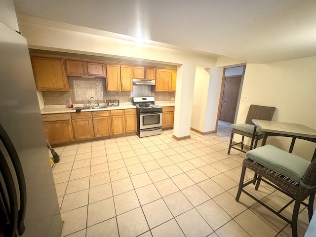 143 E 111th St, Chicago, IL 60628 - kitchen featuring appliances with stainless steel finishes, under cabinet range hood, light countertops, a sink, and light tile patterned floors