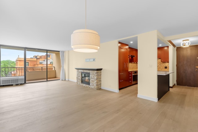 1450 N Astor St Unit 7D, Chicago, IL 60610 - unfurnished living room with light wood-style floors, a stone fireplace, floor to ceiling windows, and baseboards