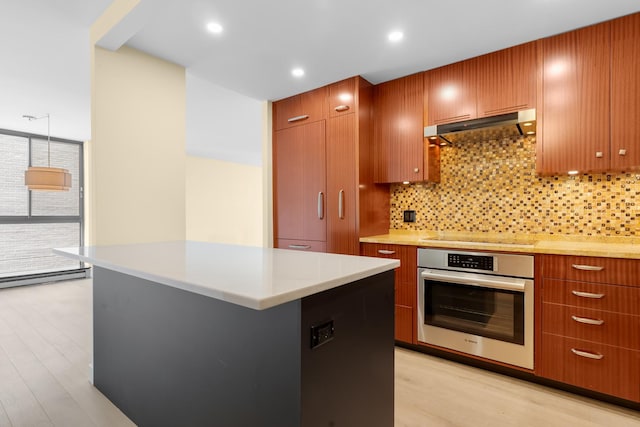 1450 N Astor St Unit 7D, Chicago, IL 60610 - kitchen with stainless steel oven, under cabinet range hood, black electric cooktop, light wood-style floors, and decorative backsplash