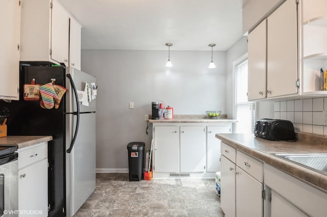 430 S Tanner Ave, Kankakee, IL 60901 - kitchen with tasteful backsplash, stove, white cabinets, and freestanding refrigerator