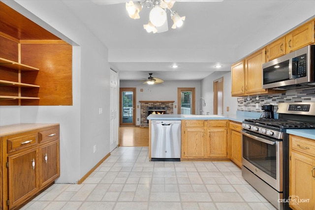 916 Shady Ln, Aurora, IL 60506 - kitchen with stainless steel appliances, a sink, a ceiling fan, a peninsula, and a fireplace