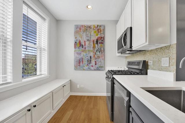1737 W Balmoral Ave Unit 1A, Chicago, IL 60640 - kitchen featuring appliances with stainless steel finishes, light wood-type flooring, decorative backsplash, recessed lighting, and white cabinetry
