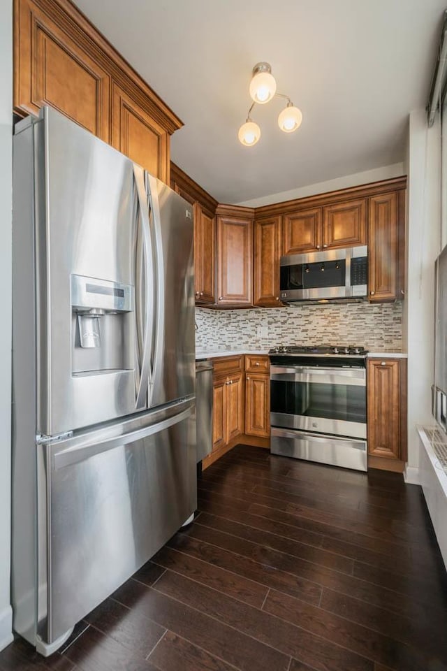 kitchen featuring stainless steel appliances, light countertops, dark wood-style flooring, and brown cabinetry
