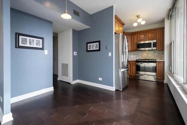 kitchen with stainless steel appliances, brown cabinets, tasteful backsplash, dark wood finished floors, and light countertops