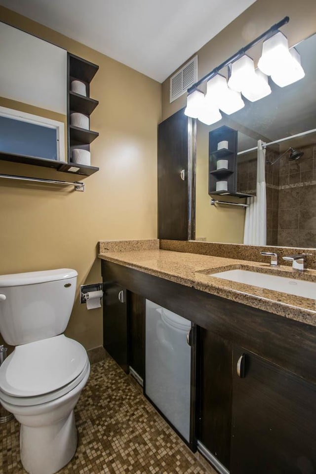 full bath with toilet, vanity, and tiled shower