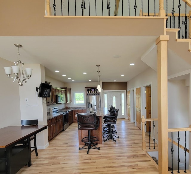 7648 N Indian Ridge Rd, East Dubuque, IL 61025 - kitchen with stainless steel appliances, light wood-style flooring, a chandelier, a kitchen bar, and decorative light fixtures
