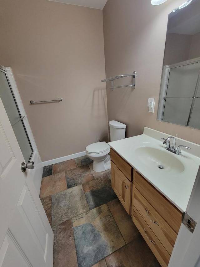 7648 N Indian Ridge Rd, East Dubuque, IL 61025 - bathroom with stone tile floors, toilet, vanity, baseboards, and a shower with door