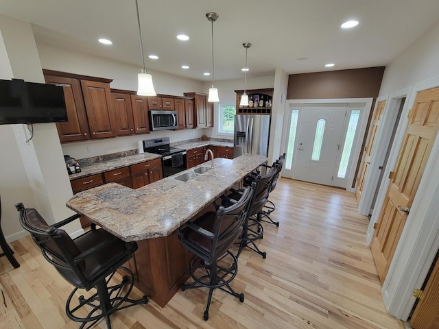 7648 N Indian Ridge Rd, East Dubuque, IL 61025 - kitchen featuring stainless steel appliances, a sink, light wood finished floors, a breakfast bar area, and light stone counters